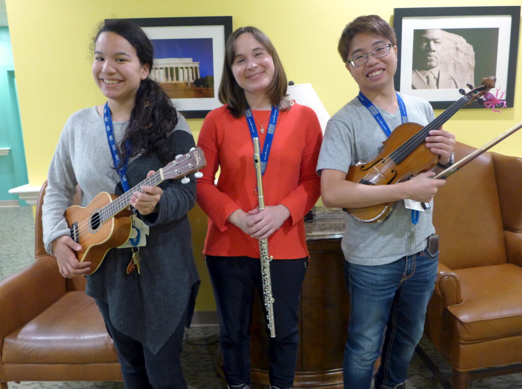 Three musicians conduct music therapy at Goddard House.